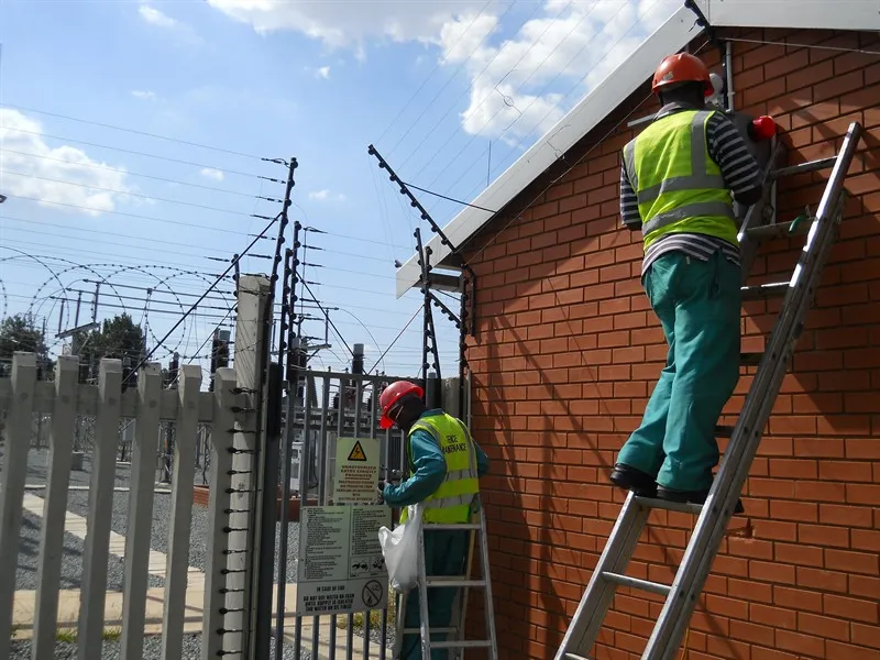 Installers in PPE working on an industrial perimeter fence