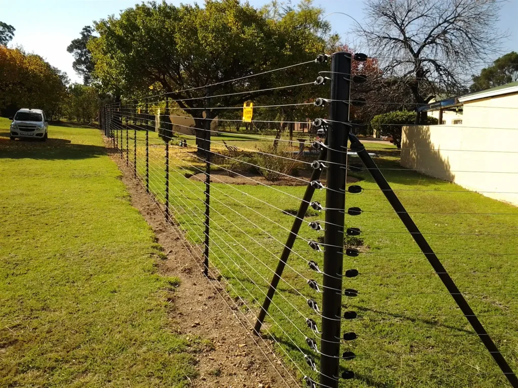 Freestanding electric fence with a strainer post running along a green smallholding