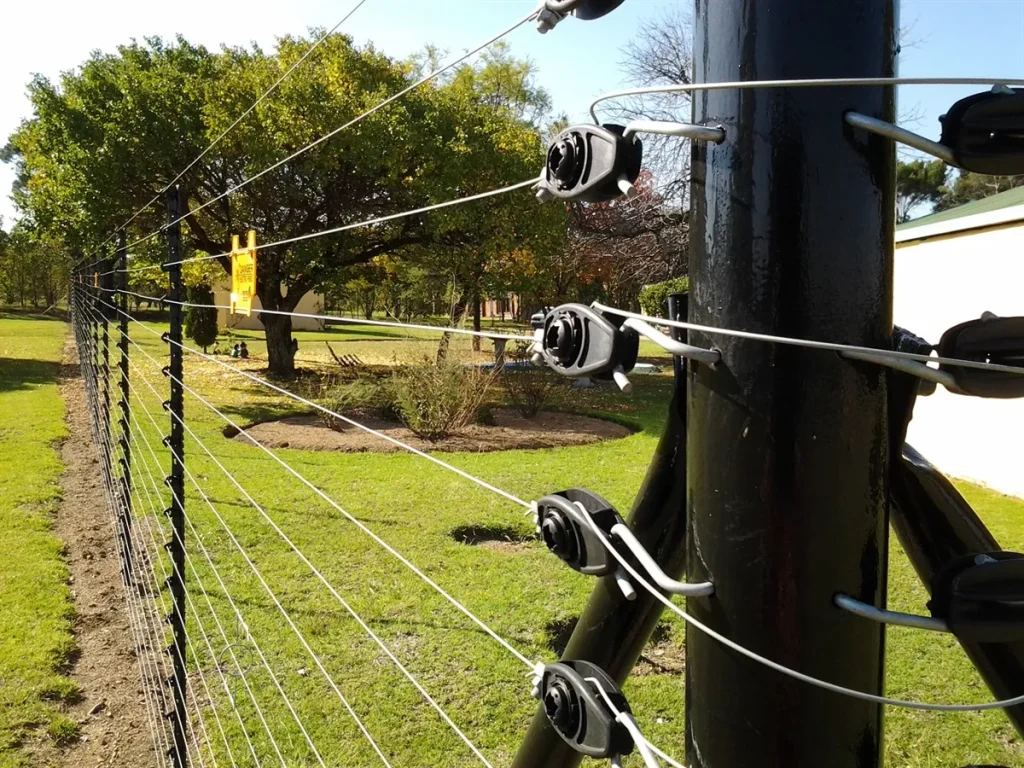 Close-up of a strainer post with neat insulators and tightly strung strands