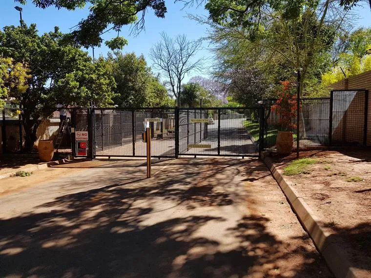 Estate entrance with automated mesh gates and an access pedestal
